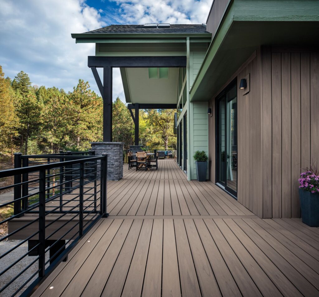 After photo of a full deck rebuild by Zenith Builders, showing a large wooden deck spanning the entire width of a modern home, featuring natural wood tones and a clear protective railing