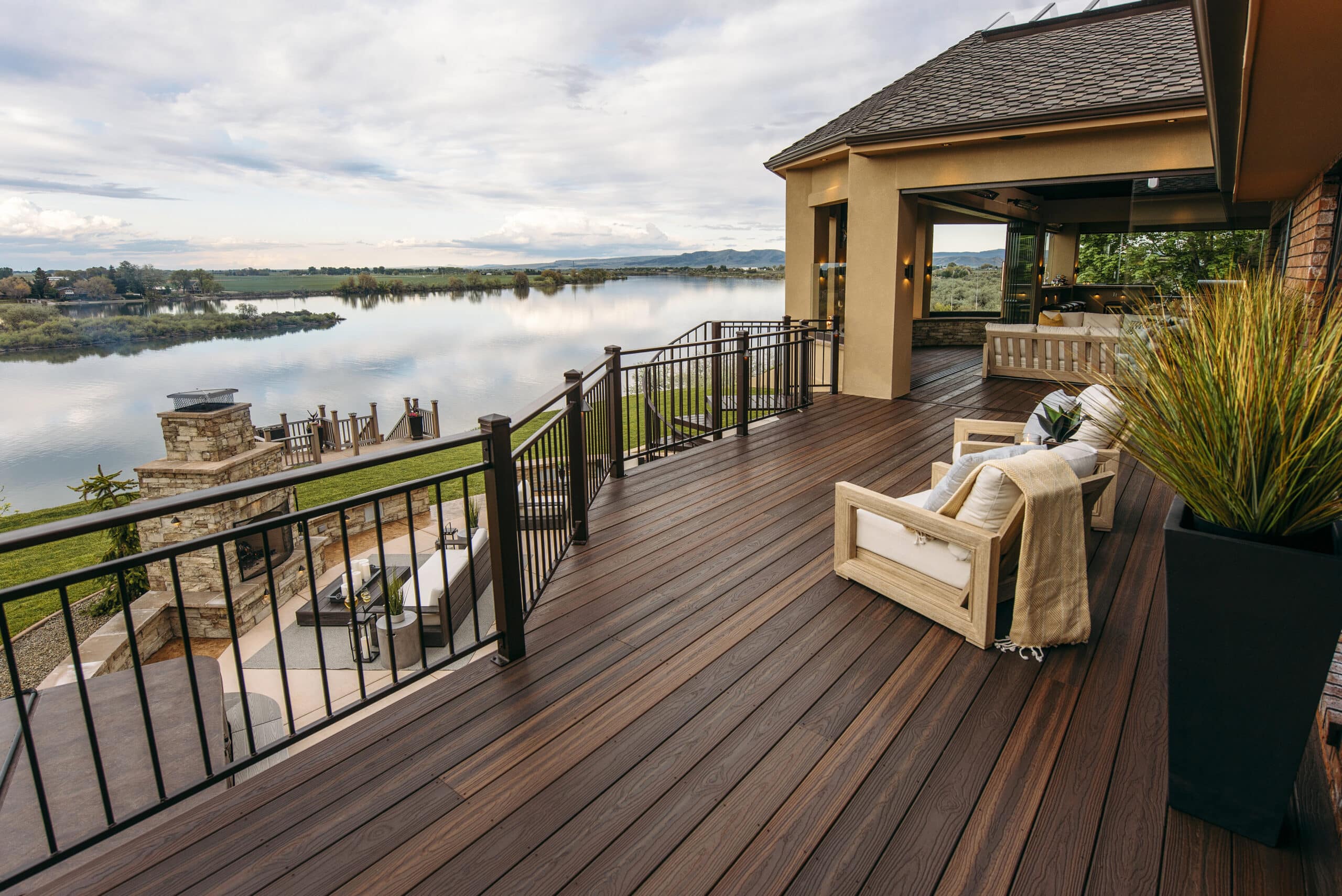 Renovated deck and patio area by Zenith Builders featuring soft blue-gray composite decking, complemented by a robust white and black balustrade that encircles the space