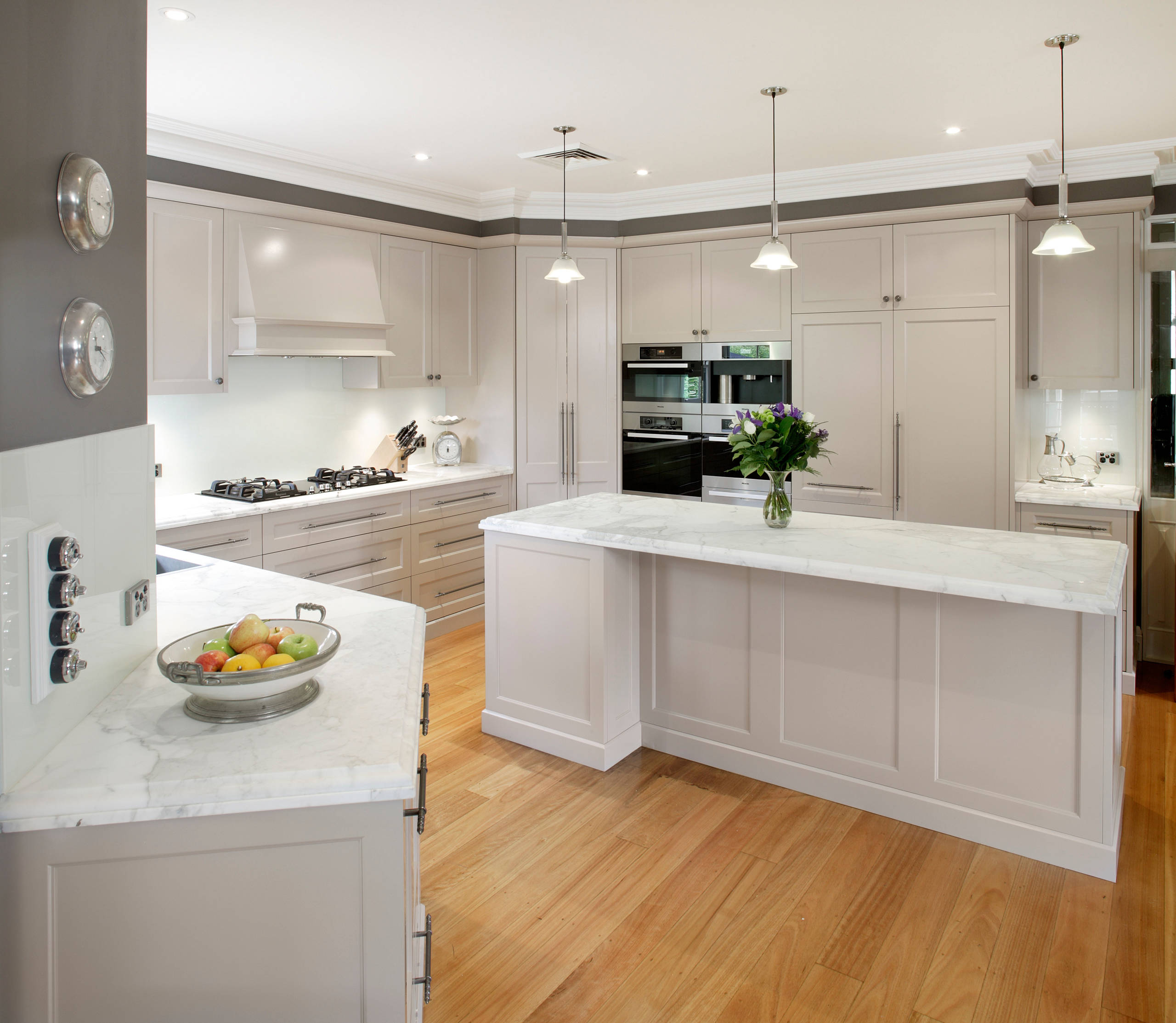 A sophisticated kitchen remodel boasting dark wooden cabinets and stainless steel appliances, completed by Zenith Builders. The elegant design is highlighted by white marble countertops and a linear tile backsplash, creating a luxurious and functional cooking space